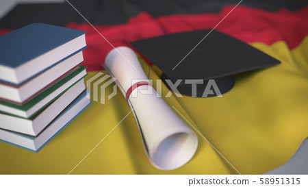 Graduation cap, books and diploma on the German flag. Higher education in Germany related conceptual 58951315