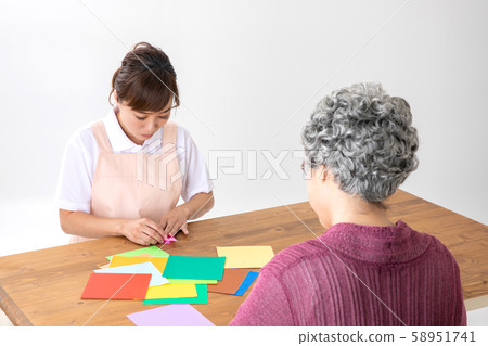 Caregivers and elderly women recreation with origami 58951741