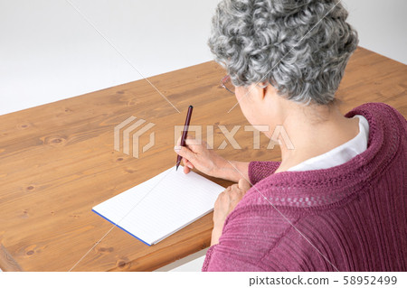 Elderly woman writing something in a notebook Elderly woman writing something in a notebook 58952499