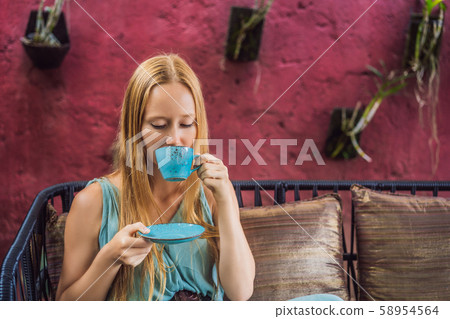 Young woman having a mediterranean breakfast seated at sofa and drinks hot aromatic coffee Young woman having a mediterranean breakfast seated at sofa and drinks hot aromatic coffee 58954564