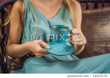 Young woman having a mediterranean breakfast seated at sofa and drinks hot aromatic coffee 58954576