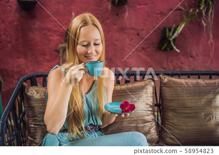 Young woman having a mediterranean breakfast seated at sofa and drinks hot aromatic coffee 58954823