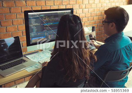 Two software developers are using computers to 58955369