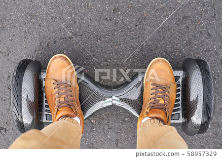 Close up of man using hoverboard on asphalt road. 58957329