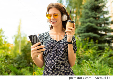A portait of young caucasian woman with perfect smile, plump lips, glasses, earphones, walks in A portait of young caucasian woman with perfect smile, plump lips, glasses, earphones, walks in 58960117