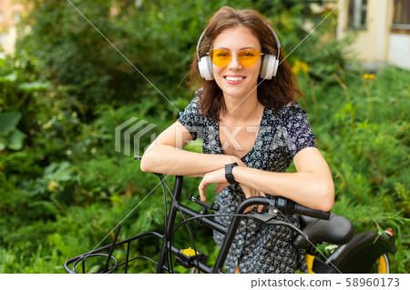A portrait of young caucasian woman with perfect smile, plump lips, glasses, earphones, walks in 58960173