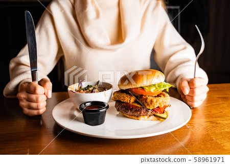 .Young woman eating burger in restaurant .Young woman eating burger in restaurant 58961971