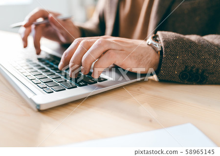Hand of young male employee or analyst over laptop keypad during work with data Hand of young male employee or analyst over laptop keypad during work with data 58965145