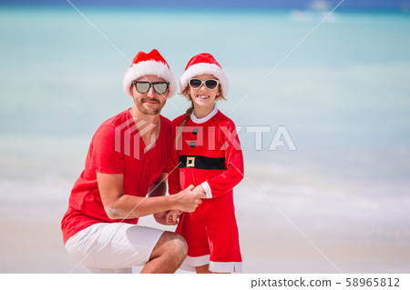 Father and daughter in Santa Hat have fun at tropical beach Father and daughter in Santa Hat have fun at tropical beach 58965812