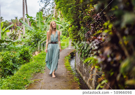 Young woman tourist in Bali walks along the narrow cozy streets of Ubud. Bali is a popular tourist 58966098