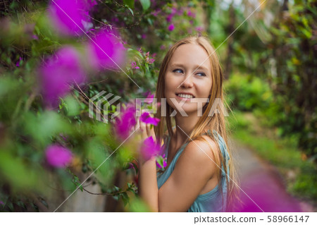 Young woman tourist in Bali walks along the narrow cozy streets of Ubud. Bali is a popular tourist Young woman tourist in Bali walks along the narrow cozy streets of Ubud. Bali is a popular tourist 58966147