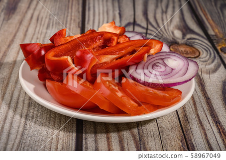 Sliced tomatoes, sweet peppers and onions in a plate on a wooden table. Sliced tomatoes, sweet peppers and onions in a plate on a wooden table. 58967049