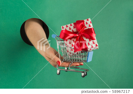Female hand holding Christmas gift box in hole 58967217