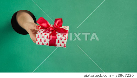 Female hand holding Christmas gift box in hole Female hand holding Christmas gift box in hole 58967220