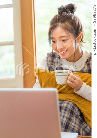年輕女子喝咖啡,看著電腦 年輕女子喝咖啡,看著電腦 58968278