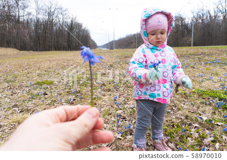 Woman holding blue snowdrop flower and little girl opposite Woman holding blue snowdrop flower and little girl opposite 58970010