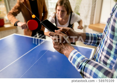 Young people playing table tennis in workplace, having fun 58970109