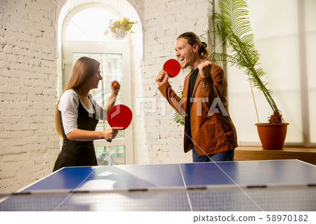Young people playing table tennis in workplace, having fun Young people playing table tennis in workplace, having fun 58970182