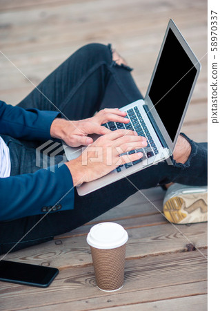 Closeup man hand working on wooden bridge with laptop, coffee and notebook Closeup man hand working on wooden bridge with laptop, coffee and notebook 58970337