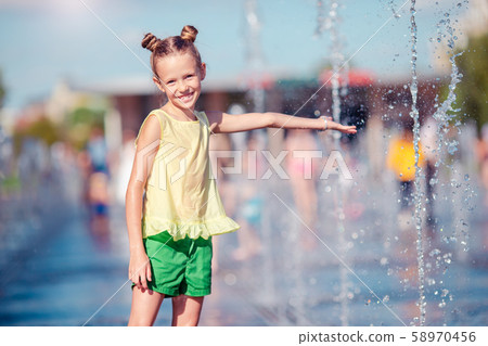 Little adorable girl have fun in street fountain at hot sunny day Little adorable girl have fun in street fountain at hot sunny day 58970456