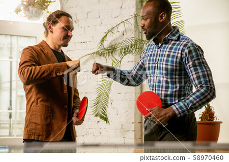 Young men playing table tennis in workplace, having fun 58970460