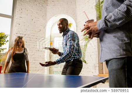 Young people playing table tennis in workplace, having fun Young people playing table tennis in workplace, having fun 58970951