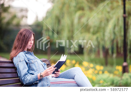 Relaxed young woman reading book Relaxed young woman reading book 58972577