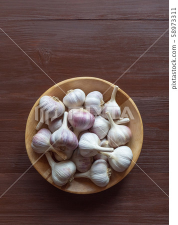Garlic in a wooden bowl on a brown table. Garlic in a wooden bowl on a brown table. 58973311