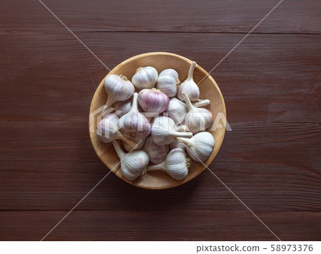 Garlic in a wooden bowl on a brown table. Garlic in a wooden bowl on a brown table. 58973376