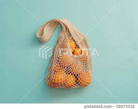 Mesh bag with fruits on blue background.Zero waste 58973516