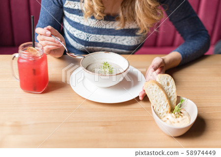 Crop of woman holding spoon and white bowl of 58974449