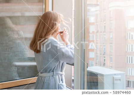 Blonde woman in bathrobe drinking her morning Blonde woman in bathrobe drinking her morning 58974460