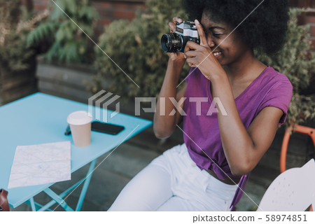Beautiful woman taking photos on her camera while sitting Beautiful woman taking photos on her camera while sitting 58974851
