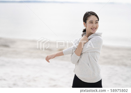 Women doing flexible exercises on the sandy beach 58975802