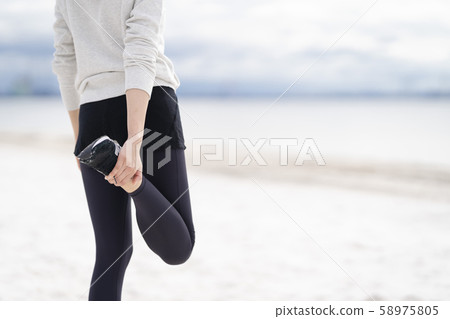 Women doing flexible exercises on the sandy beach Women doing flexible exercises on the sandy beach 58975805