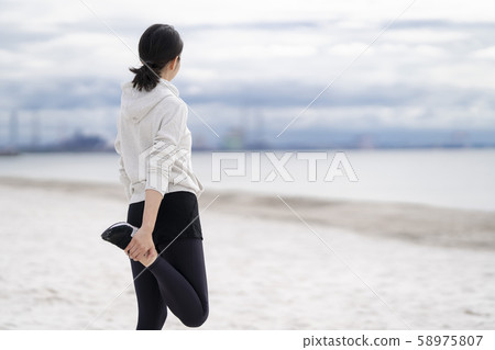 Women doing flexible exercises on the sandy beach Women doing flexible exercises on the sandy beach 58975807