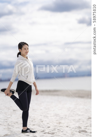 婦女在沙灘上做靈活的運動 婦女在沙灘上做靈活的運動 58975810