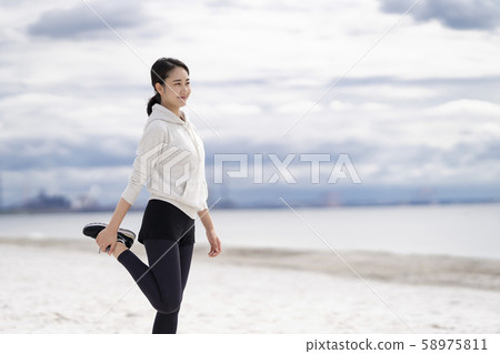 Women doing flexible exercises on the sandy beach 58975811