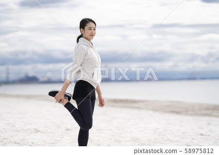 婦女在沙灘上做靈活的運動 婦女在沙灘上做靈活的運動 58975812