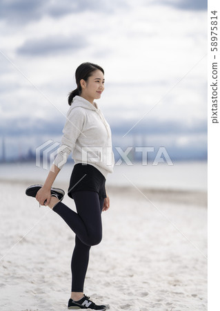 Women doing flexible exercises on the sandy beach Women doing flexible exercises on the sandy beach 58975814