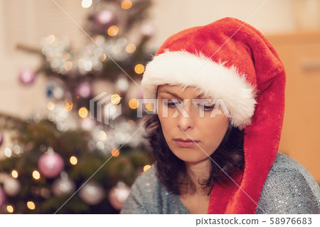 Beautiful middle age woman in santa hat sitting 58976683