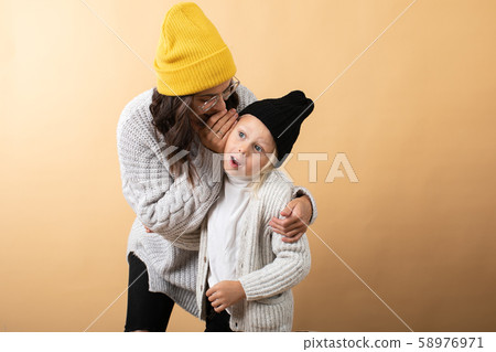 A young and energetic mother hugs and kisses her son on an orange background 58976971