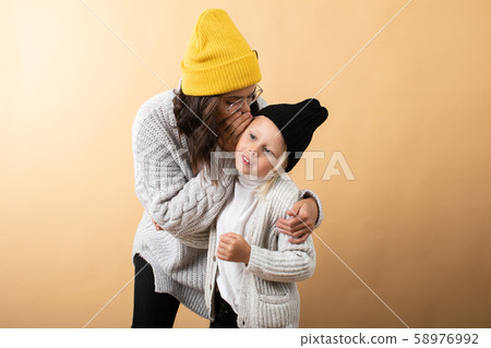 A young and energetic mother hugs and kisses her son on an orange background A young and energetic mother hugs and kisses her son on an orange background 58976992