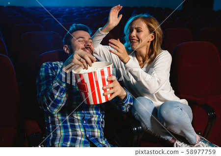 Attractive young caucasian couple watching a film at a movie theater Attractive young caucasian couple watching a film at a movie theater 58977759