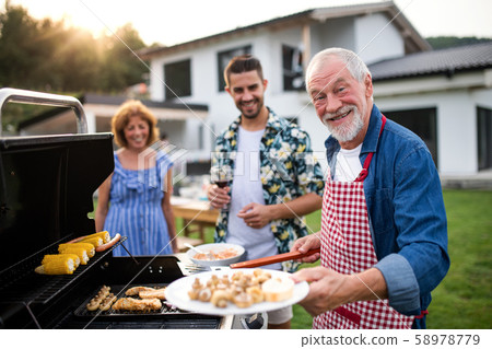 Portrait of multigeneration family outdoors on garden barbecue, grilling. 58978779