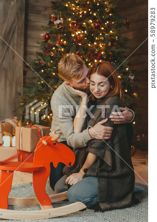 Young caucasian family mom dad son near fireplace christmas tree 58979283