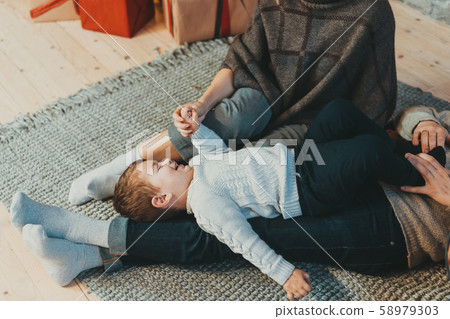 Young caucasian family mom dad son near fireplace christmas tree Young caucasian family mom dad son near fireplace christmas tree 58979303