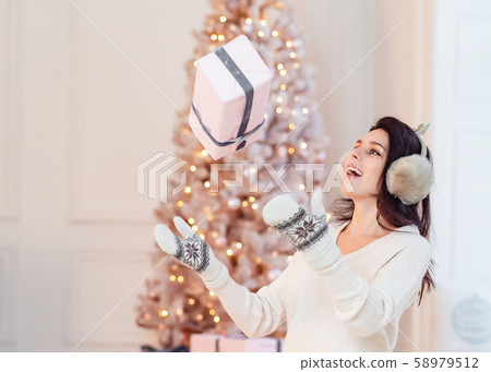 Beautiful young girl in a white dress throws up a gift. Beautiful young girl in a white dress throws up a gift. 58979512