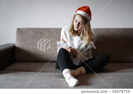 Portrait of pretty girl at Christmas writes plans for the new year 58979759
