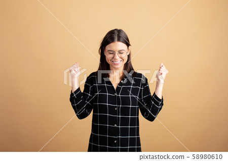 A young woman in a plaid dress stands on an orange background and shows different emotions A young woman in a plaid dress stands on an orange background and shows different emotions 58980610